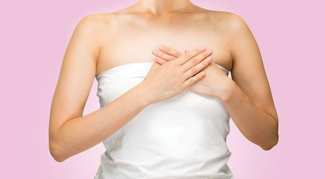 Image of a woman holding her hands over her left breast.