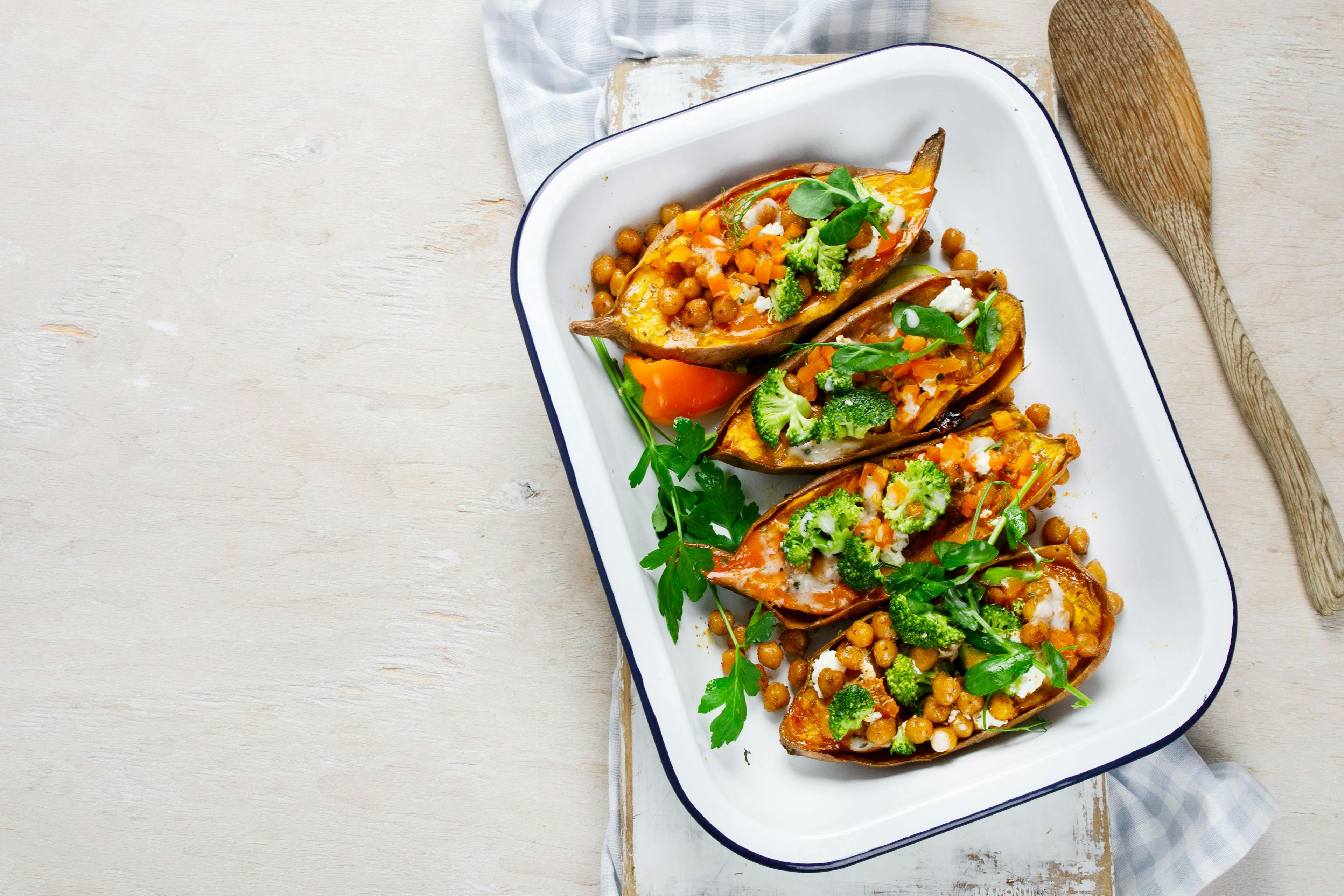 Stuffed sweet potato with spiced chickpea, dressing and herbs. | Image Credit: bit24 © - stock.adobe.com. 
