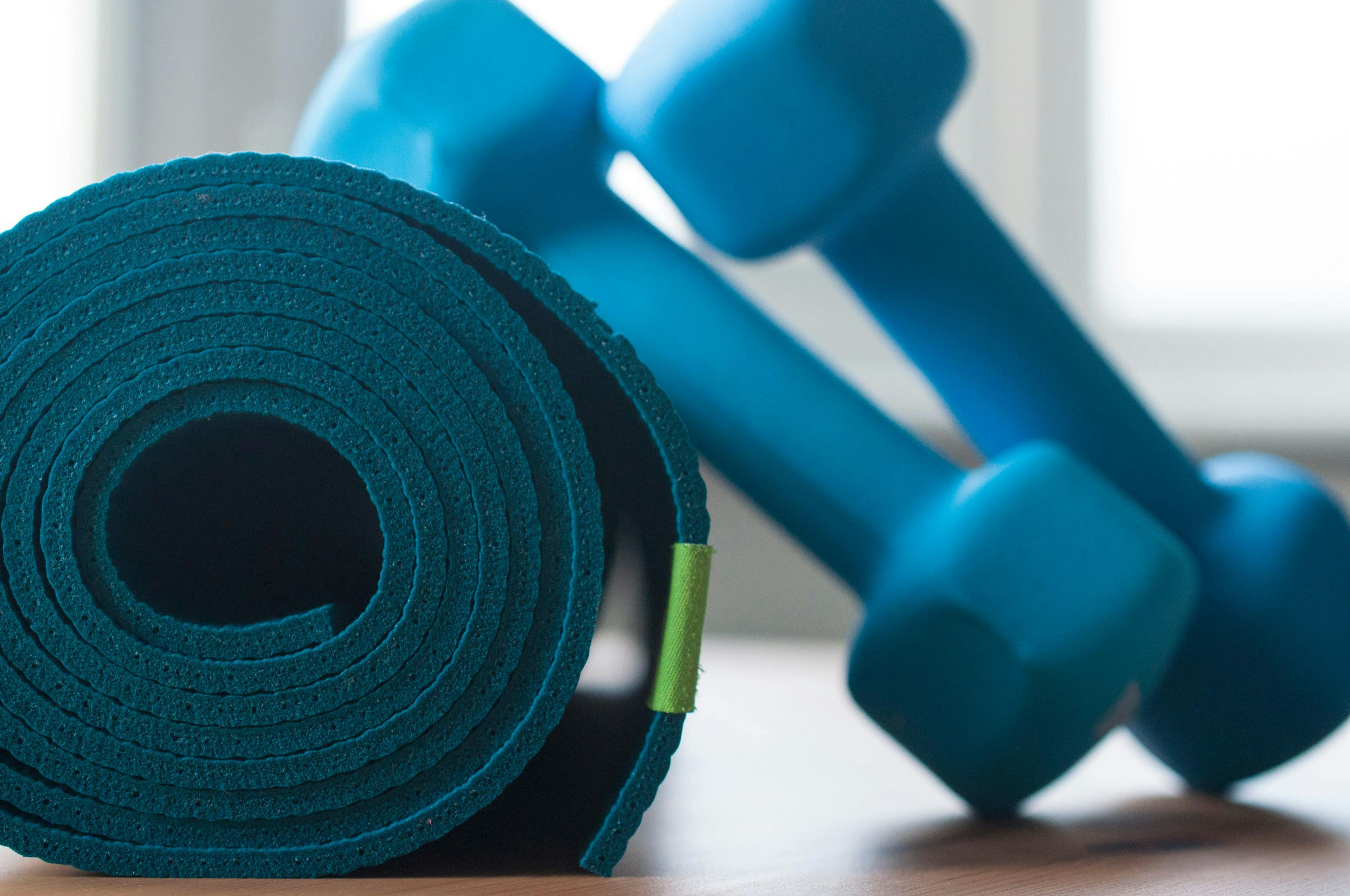 A blue rolled yoga mat with dumbbells 