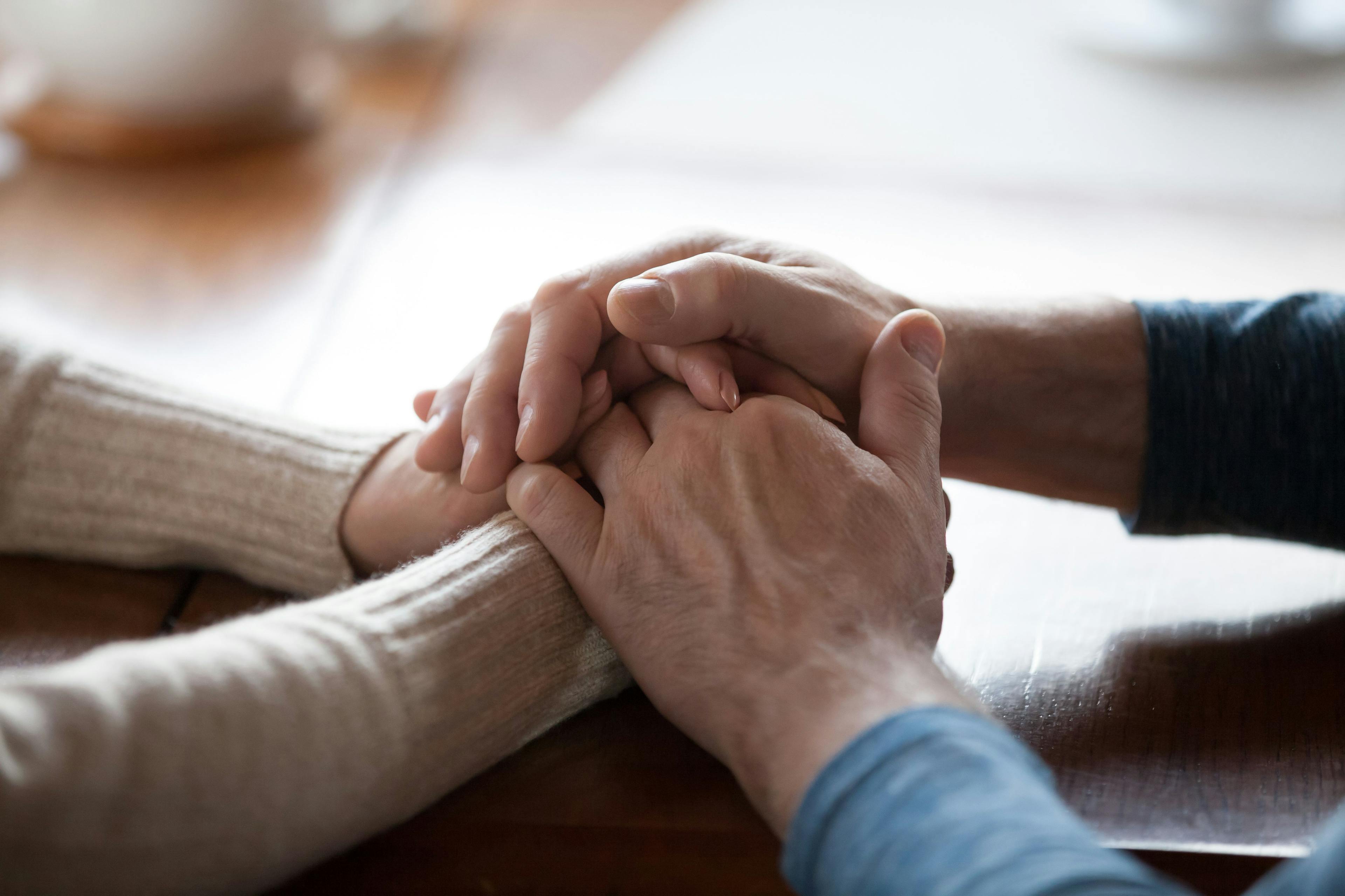Two older people holding each other's hands 